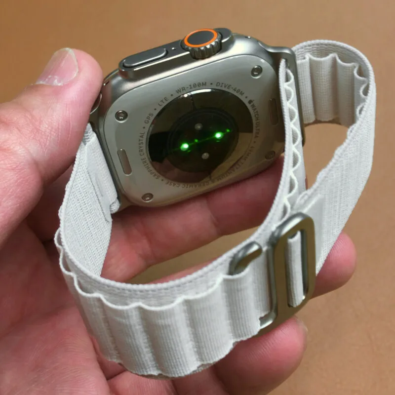 Detaliu al unui Apple Watch Ultra cu brățară albă țesută