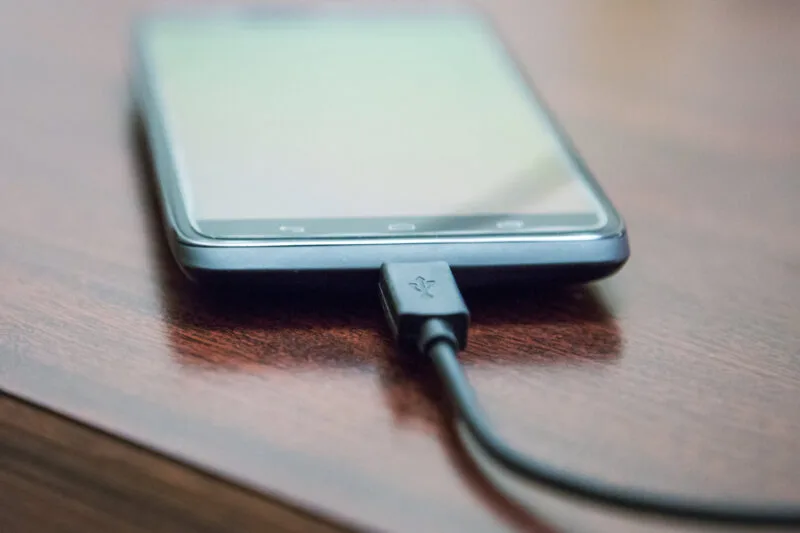 Mobile phone charging on brown wooden surface 03 17 14 33 54 utc
