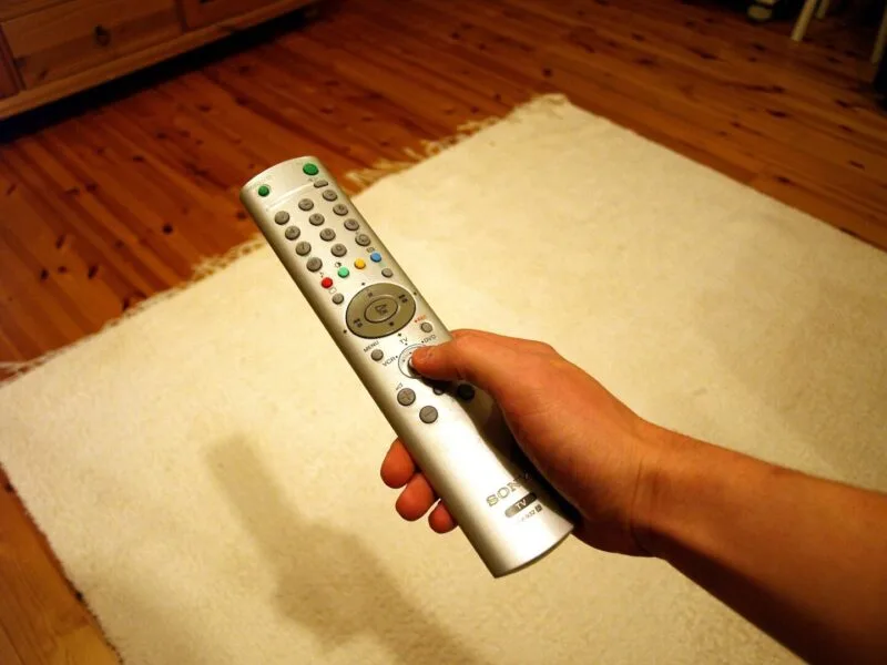 Persoană cu telecomanda în fața unui televizor OLED, evitând greșelile comune de utilizare
