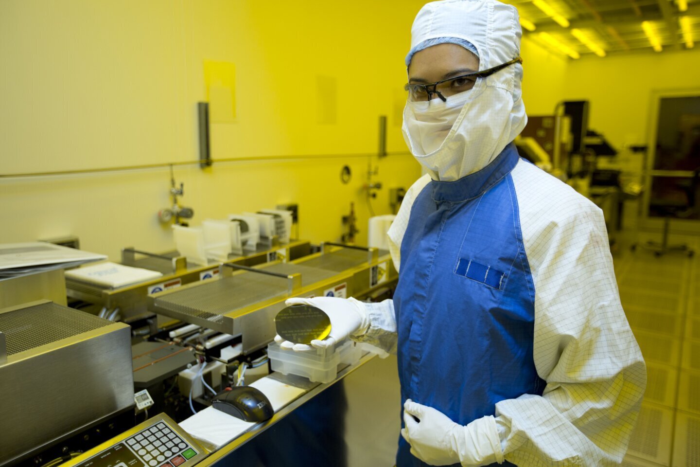 Cercetător manipulând un wafer de siliciu, ilustrând cercetarea privind gestionarea căldurii la nivel atomic (phonon focusing) în semiconductori