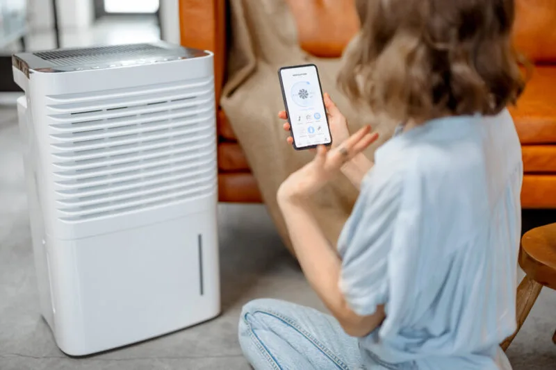 Woman controls a dehumidifier with her smartphone 03 24 04 25 59 utc