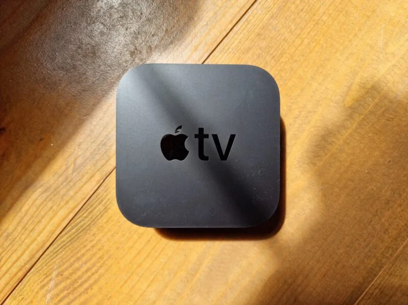 Cutia Apple TV 4K alături de telecomanda cu suprafață tactilă