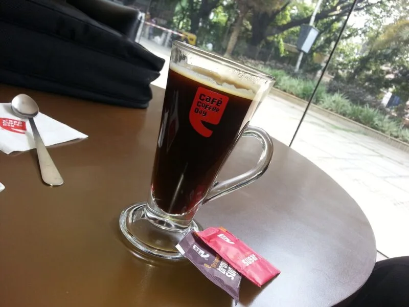 Ceașcă albă cu cafea espresso proaspăt preparată, așezată pe o farfurioară