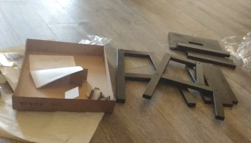 Piese și șuruburi de mobilă IKEA împrăștiate pe podea înainte de asamblare