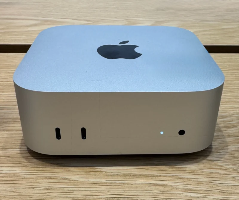 Mac mini din 2024, cu carcasă compactă de aluminiu, așezat pe birou