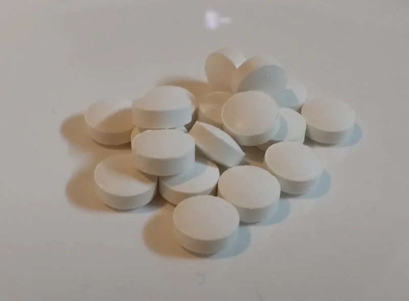 Capsule de vitamina D scoase din flacon, așezate pe o suprafață albă