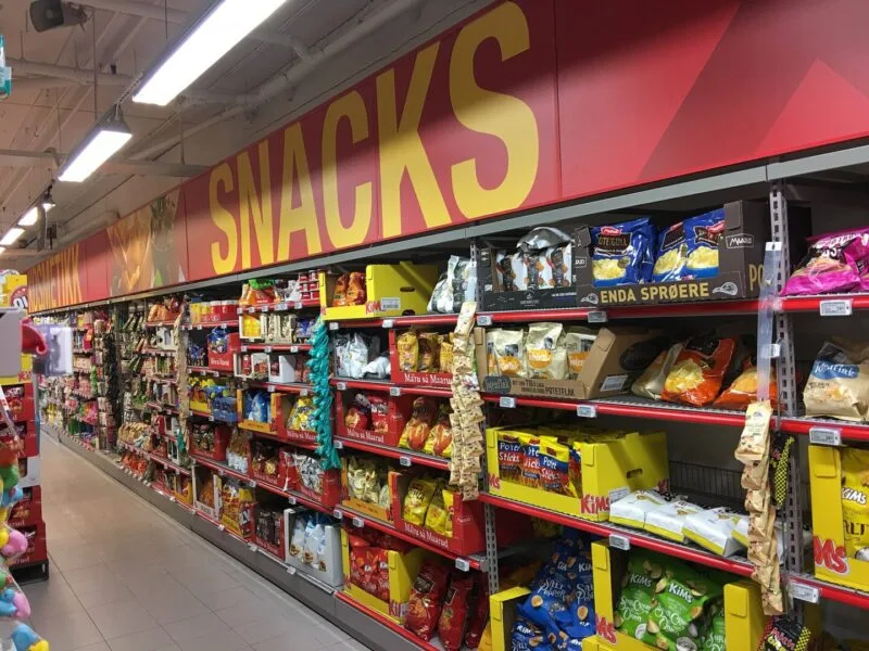 Raft de supermarket plin cu pungi de chipsuri și alte snacksuri ultraprocesate