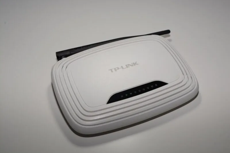 Router Wi-Fi TP-Link alb, cu antenă, fotografiat pe fundal deschis
