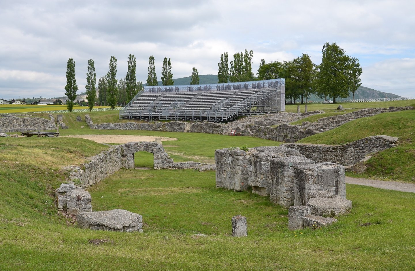 Arena și zidurile de piatră ale unui amfiteatru roman, înconjurate de iarbă