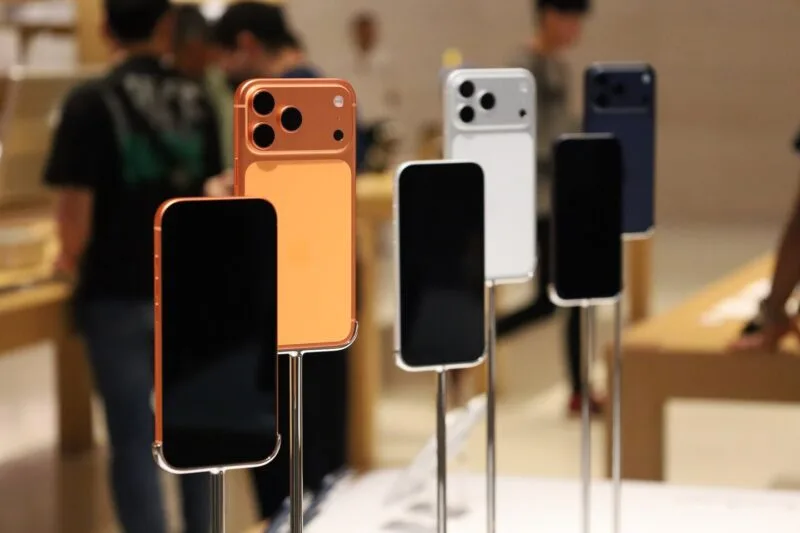Clienți într-un magazin Apple, în fața standurilor cu iPhone-uri