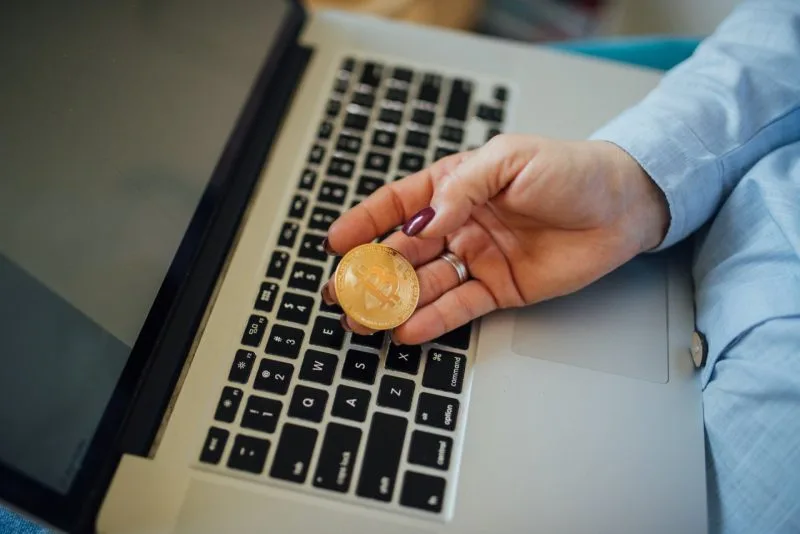 Mână care ține o monedă aurie decorativă cu simbolul Bitcoin