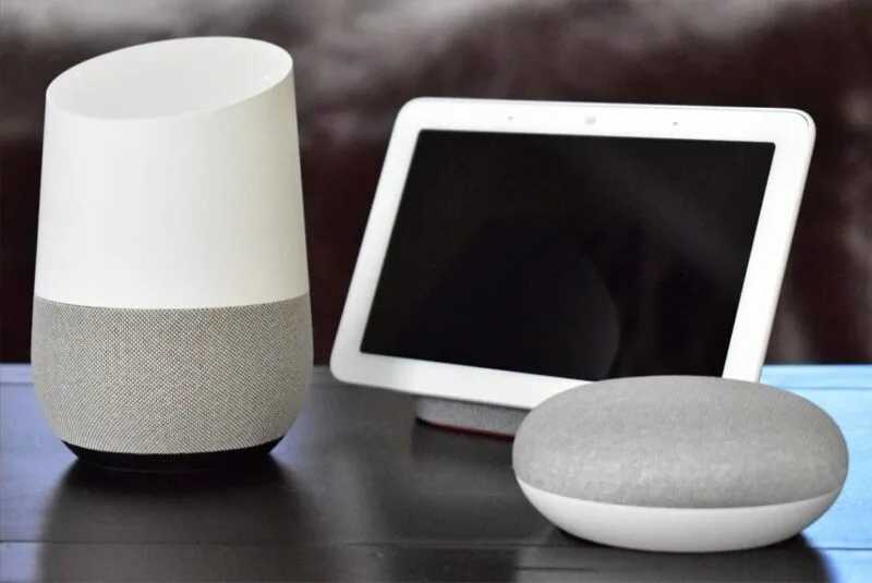 Boxa Google Home, un Nest Hub și un Google Home Mini așezate pe o masă