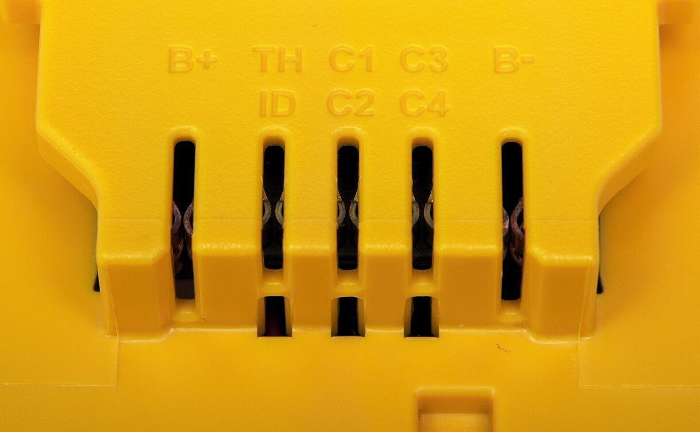 Contactele electrice ale unui acumulator pentru scule electrice, unde se vede diferența dintre volți sau wați