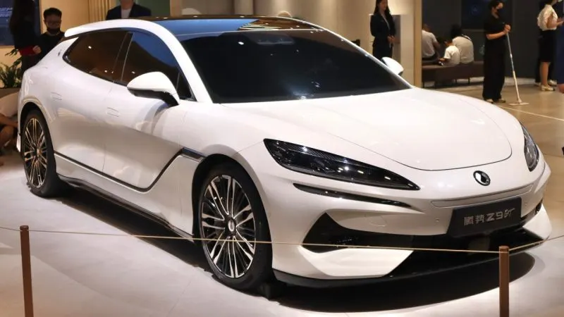Mașina electrică Denza Z9 GT albă, văzută din față-lateral, expusă pe standul unui salon auto