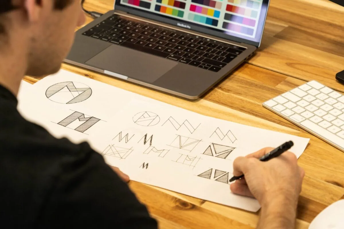 Machete de logo, afișe și materiale de branding așezate pe o masă de design grafic