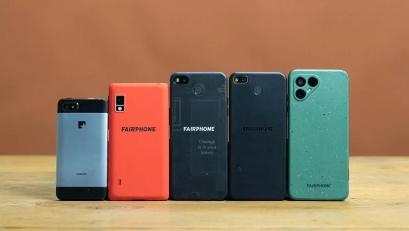 Cinci generații de telefoane Fairphone așezate una lângă alta pe o masă de lemn