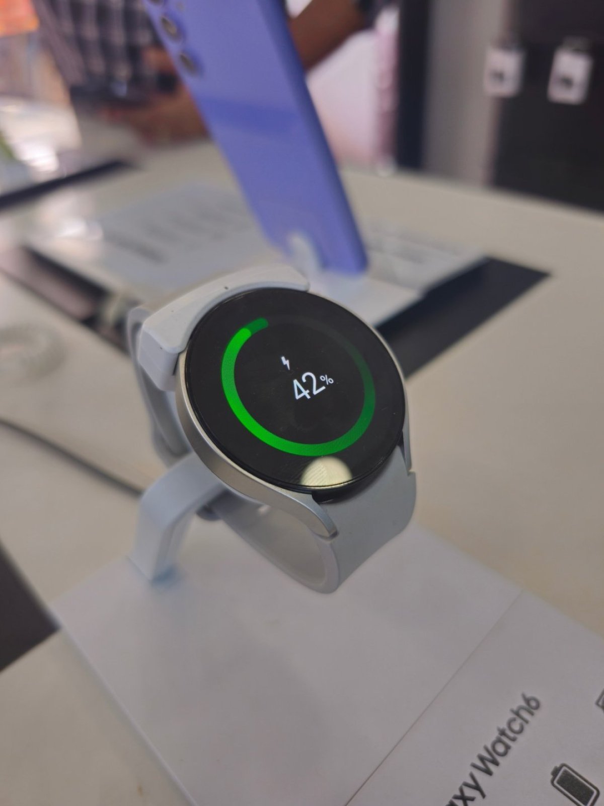 Un Samsung Galaxy Watch 6 așezat pe o suprafață, cu ecranul aprins
