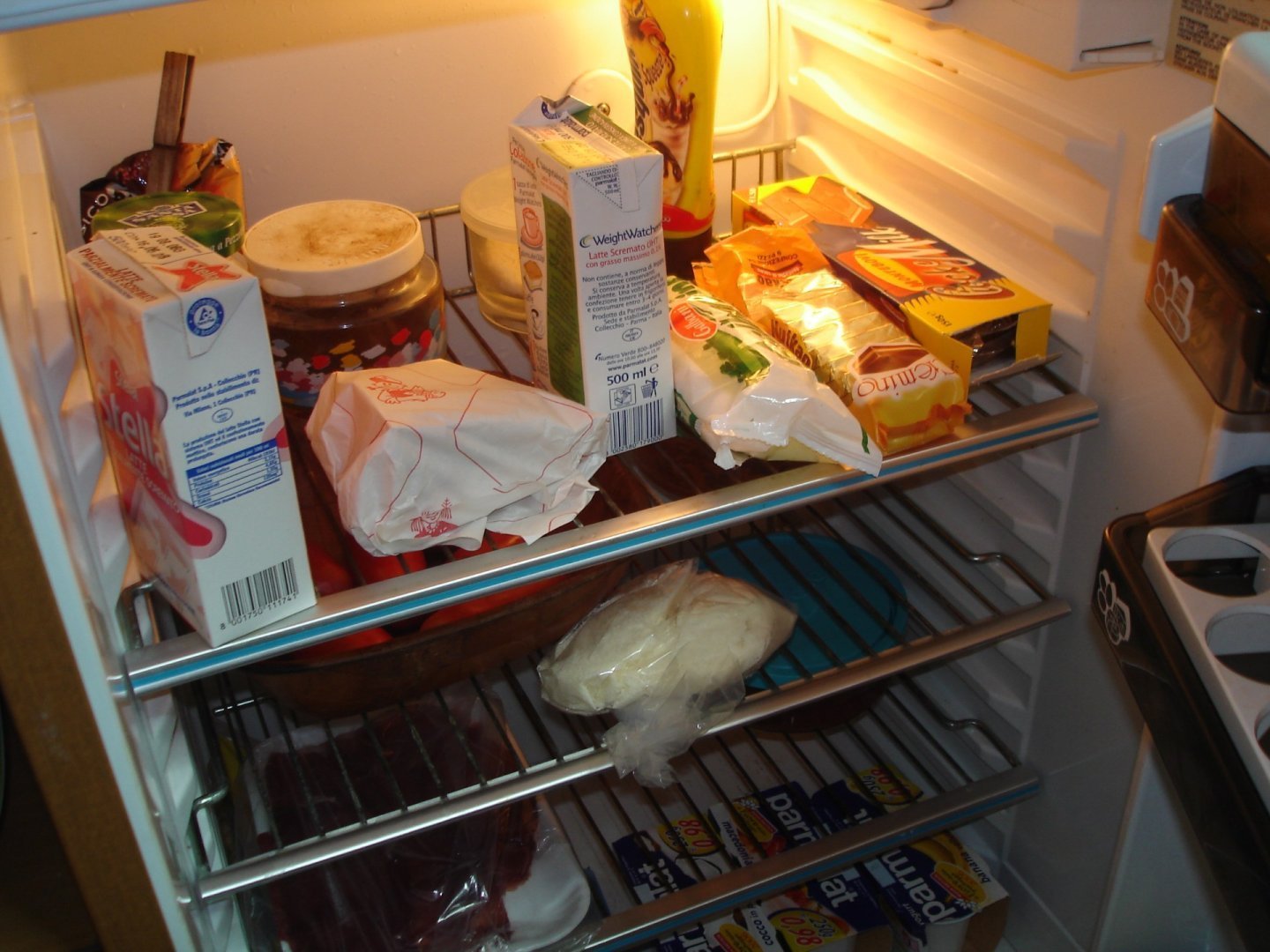 Rafturi din sticlă și sertare de plastic în interiorul unui frigider casnic