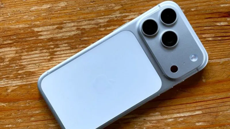 iPhone 17 Pro argintiu, cu cele trei camere din spate, așezat pe o masă de lemn