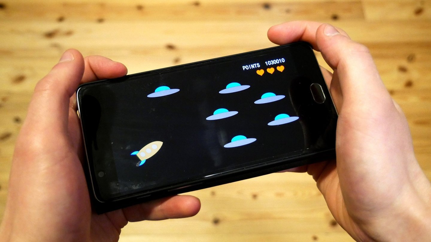 Utilizator care se joacă pe un smartphone ținut în mâini