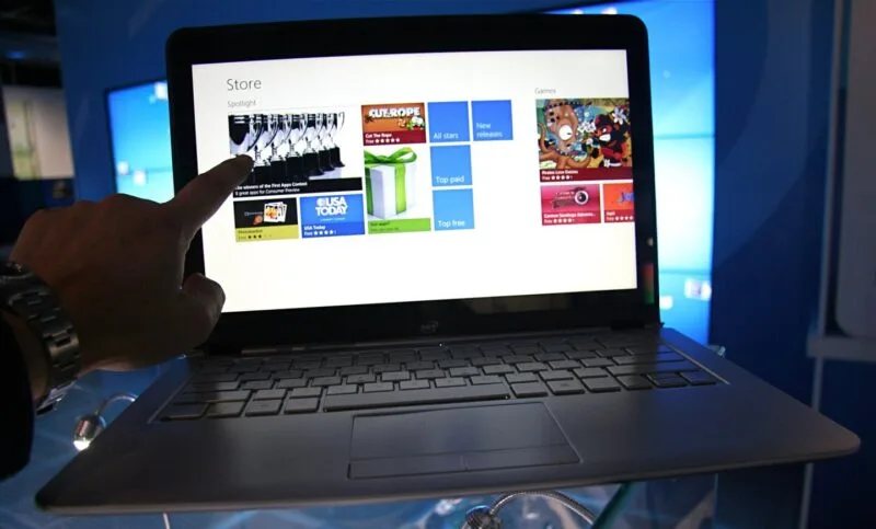 Laptop subțire deschis pe un birou, cu sistemul de operare pornit
