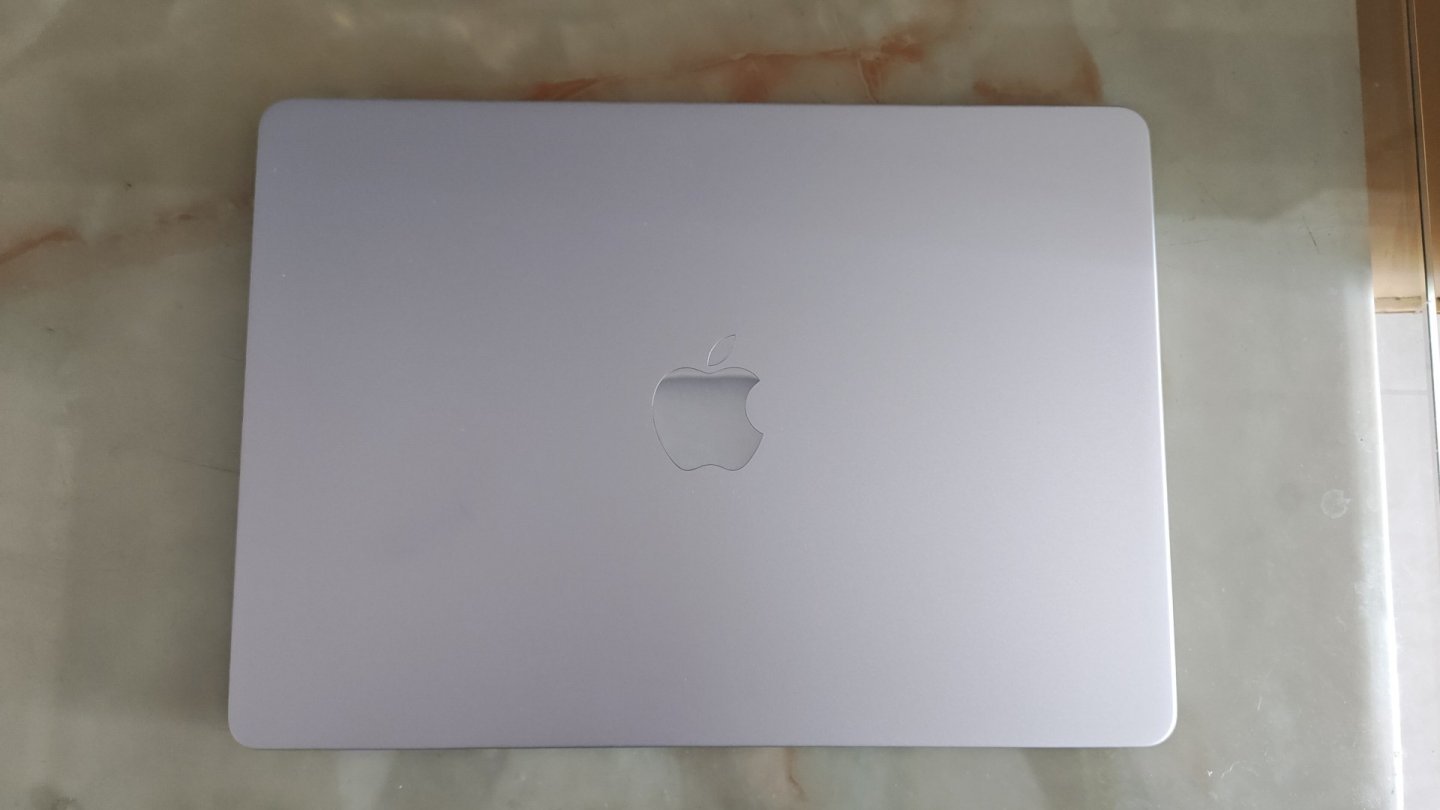 MacBook în somn MacBook Air argintiu cu capacul închis, așezat pe o masă de marmură