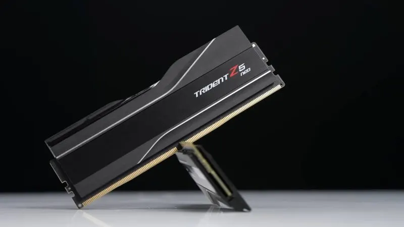 AMD EXPO Modul de memorie RAM DDR5 cu radiator negru, așezat înclinat pe un suport, fotografiat pe fundal negru