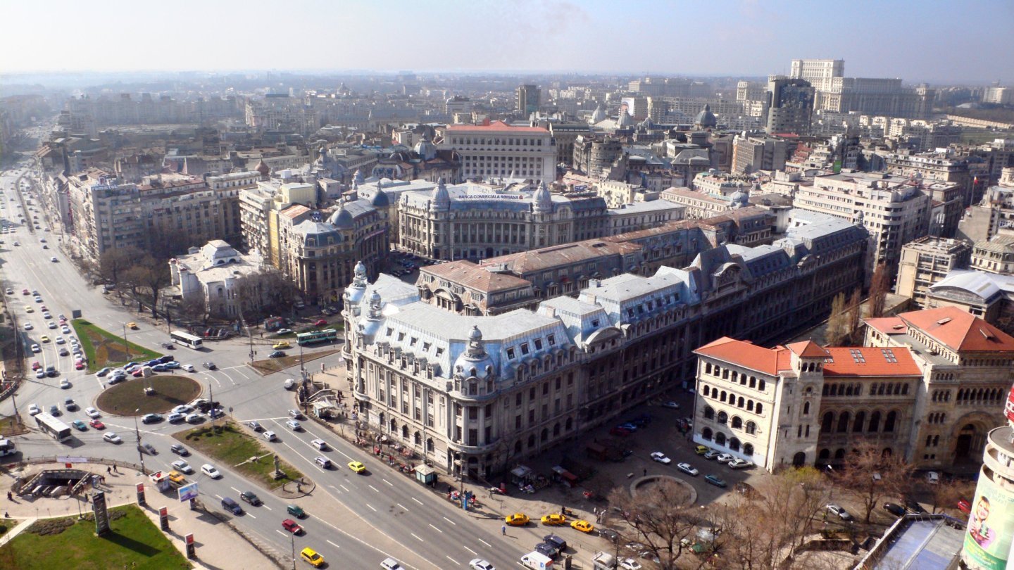 Vedere de sus asupra Bucureștiului, cu blocuri, clădiri de birouri și străzi în lumina zilei