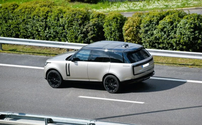 Range Rover de culoare deschisă fotografiat din trei sferturi față