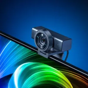 Camera web Razer Kiyo V2 Pro, neagră, prinsă cu clema pe marginea de sus a unui monitor, pe fundal albastru