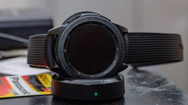 setări Galaxy Watch Ceas inteligent Samsung Galaxy Watch cu ramă rotativă și curea neagră, așezat pe masă