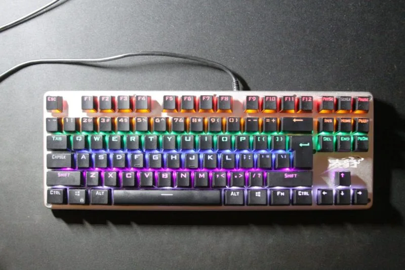 Tastatură mecanică de gaming cu fir și iluminare RGB, pe un birou închis la culoare
