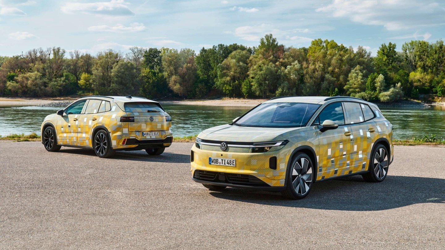 Două prototipuri Volkswagen ID. Tiguan cu folie de camuflaj galbenă, parcate lângă un râu