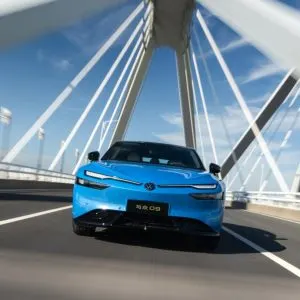Sedanul electric Volkswagen ID. UNYX 09, vopsit în albastru, rulând pe un pod suspendat cu hobane