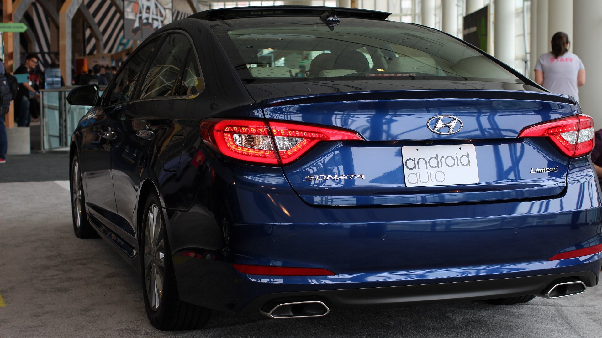 Spatele unui Hyundai Sonata albastru cu o plăcuță Android Auto, la o expoziție