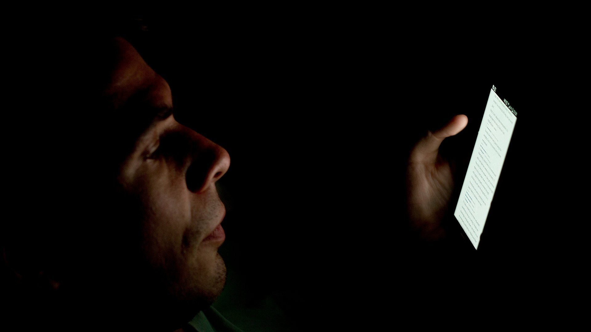 Persoană care se uită la telefon în întuneric, simbol al fraudelor după atacul de la Depozitarul Central