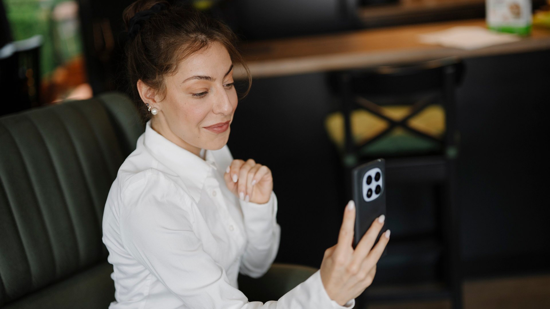 Breșă Signal: o femeie într-o cafenea ține un smartphone în mână și vorbește într-un apel video