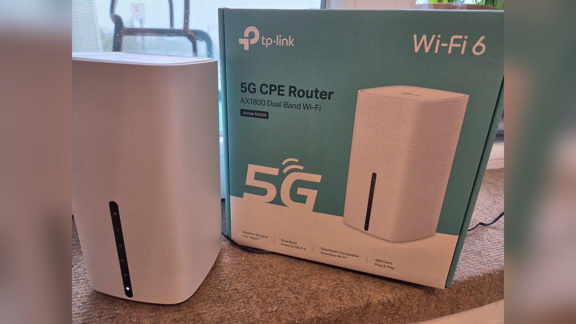 Routerul TP-Link Archer NX200 lângă cutia pe care scrie 5G CPE Router AX1800 Wi-Fi 6