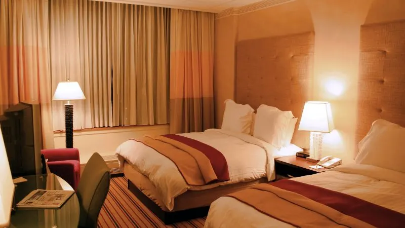 Cameră de hotel cu pat dublu, noptiere și lămpi aprinse
