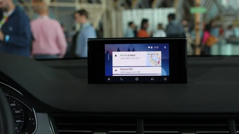 Bord de mașină cu un ecran central care afișează interfața Android Auto, fotografiat într-o expoziție