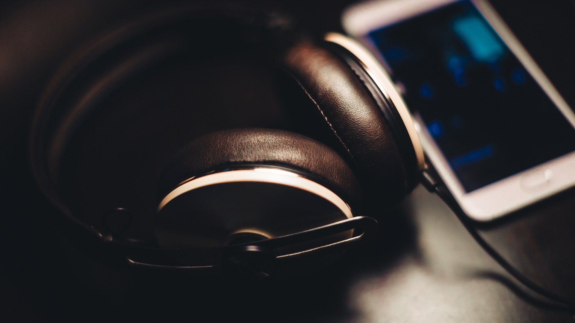 Căști over-ear lângă un smartphone folosit pentru streaming muzical, de exemplu în YouTube Music