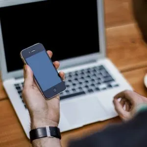 Utilizator care folosește un smartphone lângă laptop, ilustrație pentru falimentul Character.ai