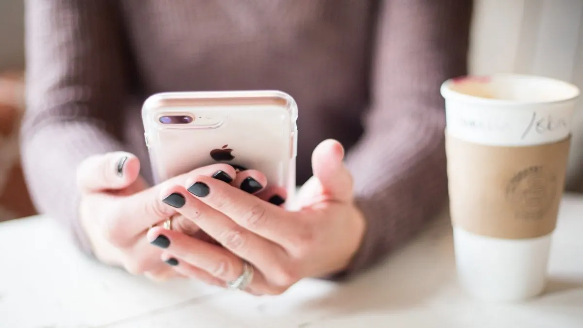algoritmul Facebook Algoritmul Facebook: o utilizatoare derulează feedul pe un smartphone, lângă o cafea