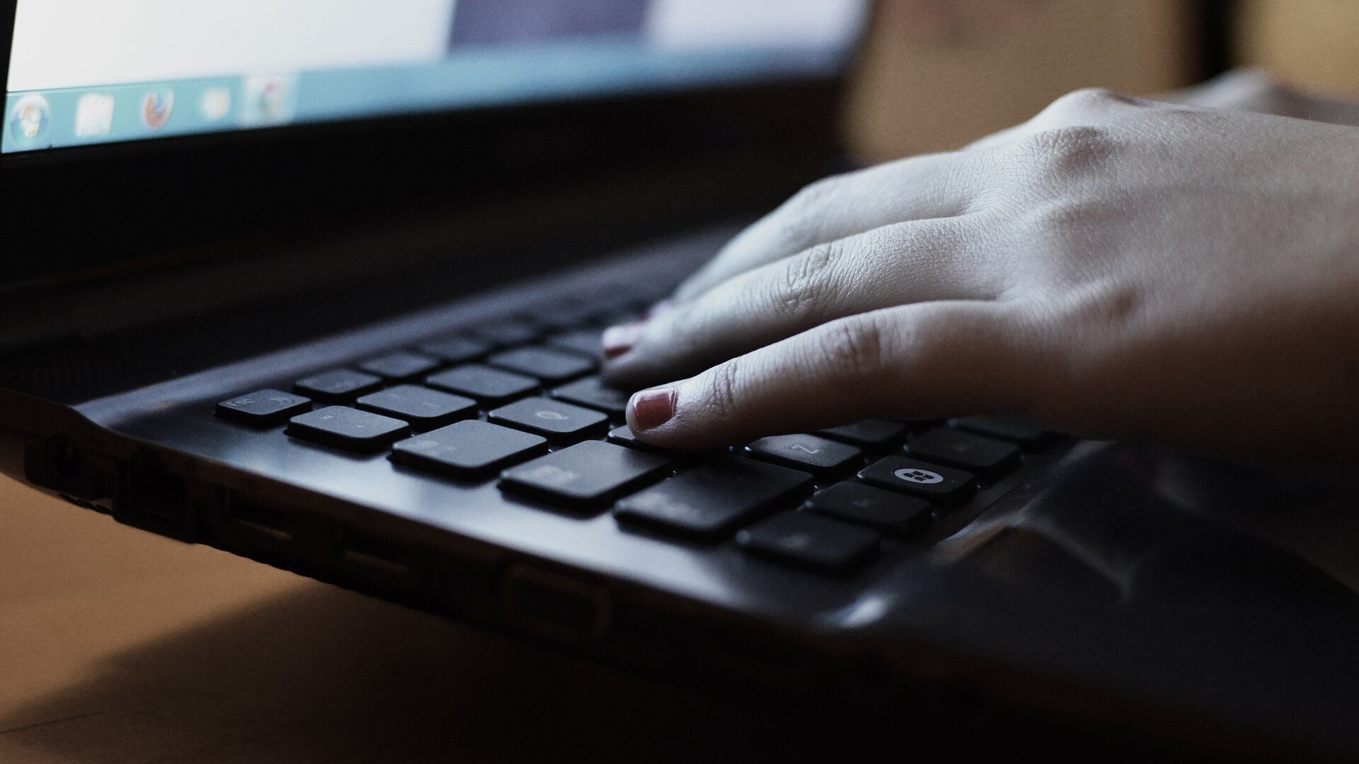 Mână pe tastatura unui laptop, ilustrație despre site-uri false ANAF și verificarea adresei înainte de introducerea datelor