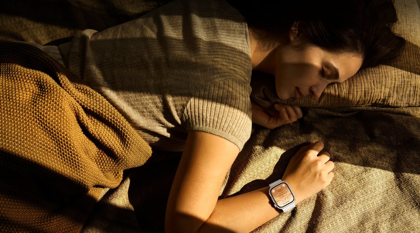 Femeie care doarme pe o pătură, cu ceasul HUAWEI WATCH D3 la încheietură, într-o cameră slab luminată