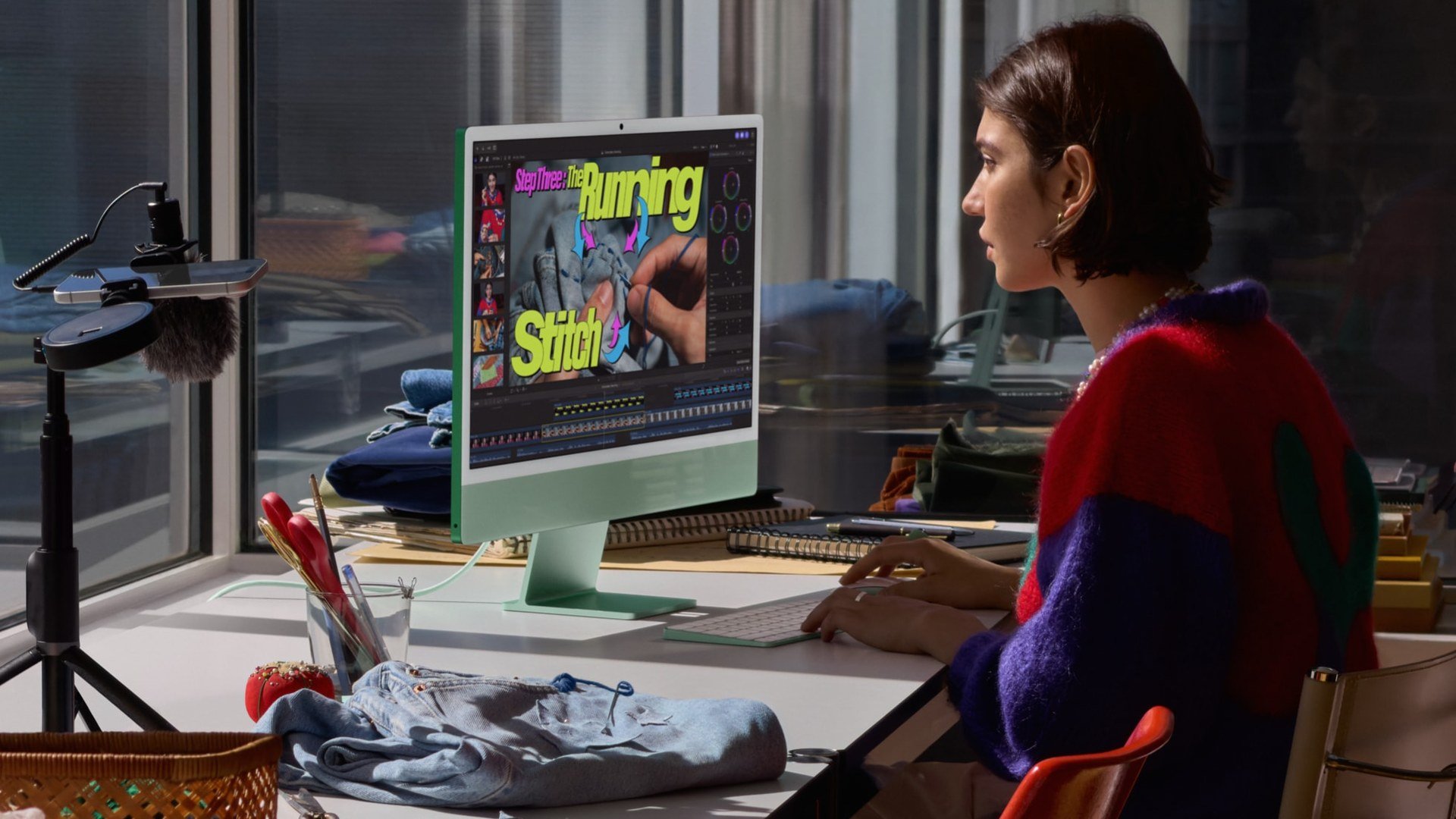 O femeie editează un clip în Final Cut Pro pe un iMac cu M6 verde, cu tastatură asortată, la un birou lângă fereastră