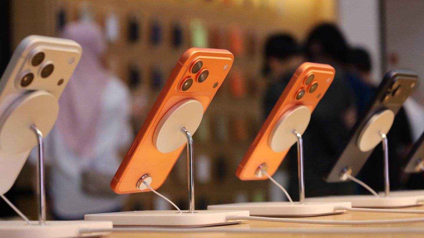 iPhone Duo Mai multe telefoane iPhone 17 Pro portocalii pe suporturi de prezentare într-un magazin Apple