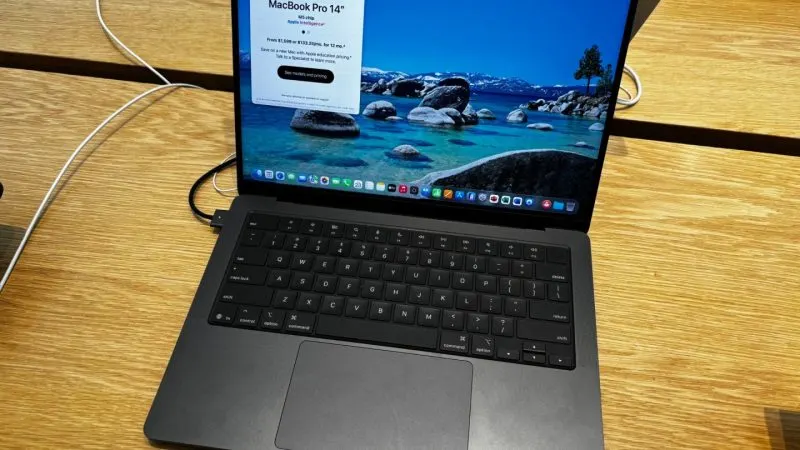 MacBook Pro de 14 inci, negru, cu M5, deschis pe o masă din lemn