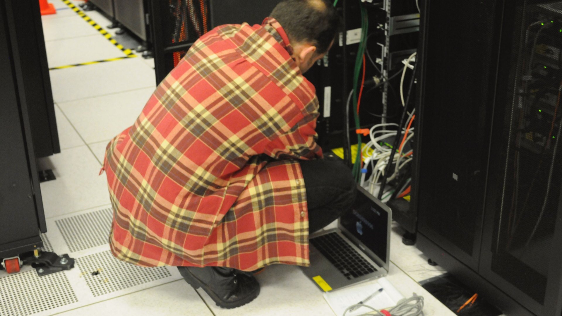 Tehnician cu laptop la un rack de servere, ilustrând actualizarea serverelor după PHP2Shell