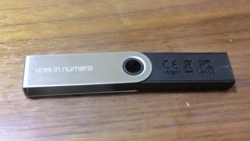 Portofel hardware Ledger Nano S, văzut din spate, pe un birou din lemn